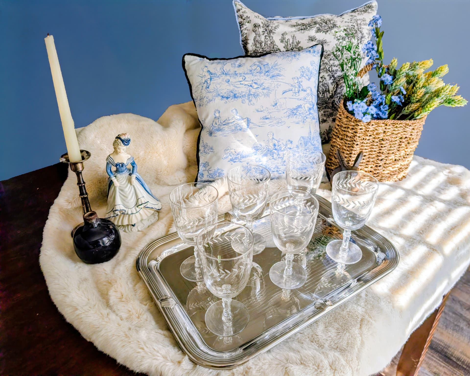 A styled serving tray with wine glasses, candle, and florals