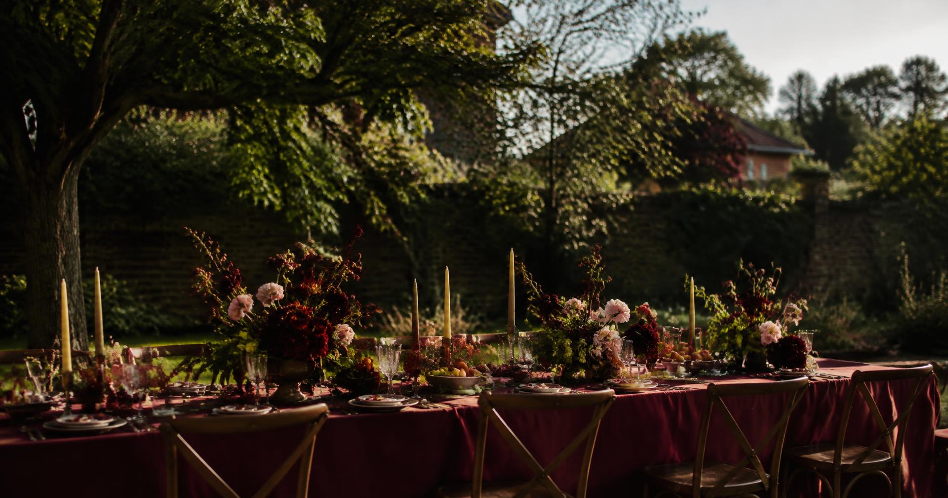 An intimate garden dinner styled with burgundy linens and sculptural flowers